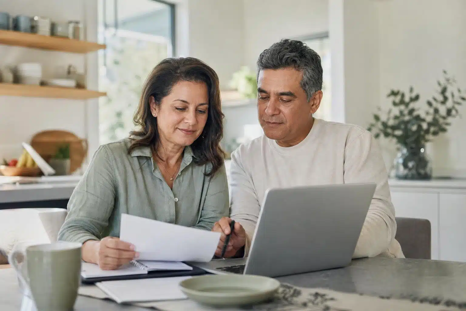 Casal brasileiro nos Estados Unidos revisa documentos de Medicare e planejamento de aposentadoria à mesa.